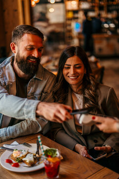 Couple paying for breakfast with contactless smartphone payment