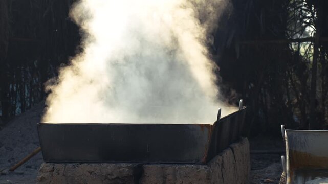 Natore, Bangladesh - 23 May 2026: View of thick white steam rising from a large metal vat on a traditional clay stove during food production.