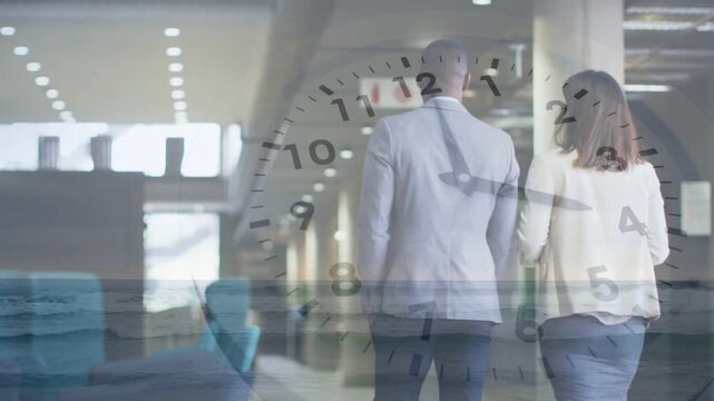 Two biz staff walking hall talking heading to sign clock overlay over subjects woman tapping device