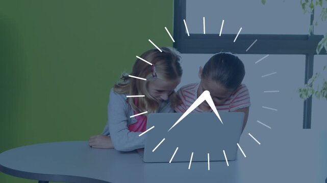 Two girls leaning at table tapping laptop activating spinning clock for school timing then smiling