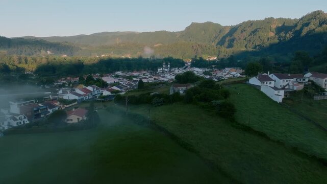 Aerial view of geothermal fumaroles in Furnas, Sao Miguel Island, with plumes of white volcanic steam rising above the lush valley landscape.