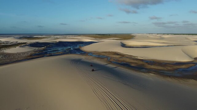 Lencois Maranhenses National Park &ndash; Cinematic aerial tracking shot of quad bikes at golden hour