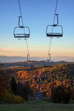 Empty ski chairlifts over autumn forest at sunset in Poiana Brasov, Romania
