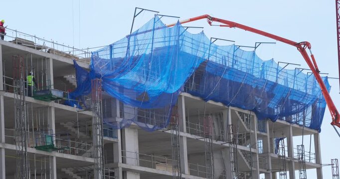Spain, Madrid, May 25 -20226: Concrete pump machine working on a residential building under construction in Valdebebas, Madrid, Spain. Workers and scaffolding visible on the upper floor during urban d