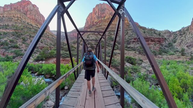 Following Man Backpacking into Grand Canyon Over Bridge on the North Kaibab Trail