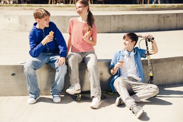 Fototapeta premium Happy smiling diverse group of teen boys and girl eating tasty ice cream on the street
