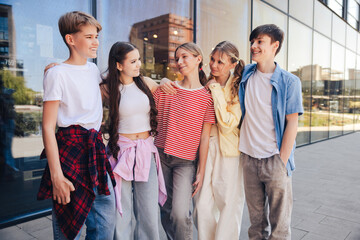 Diverse group of smiling positive teen girls and boys hugging talking together on the street © Maria Vitkovska