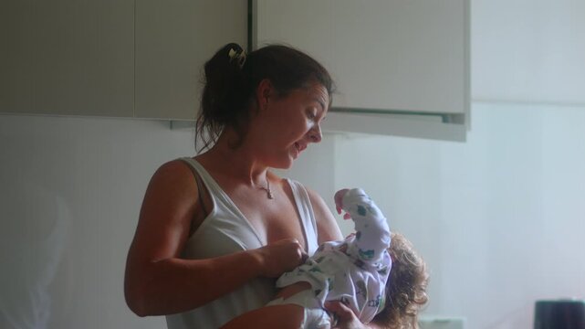 Mother asking toddler to be quiet while holding child in kitchen capturing parenting boundaries, negotiation and authentic everyday family life