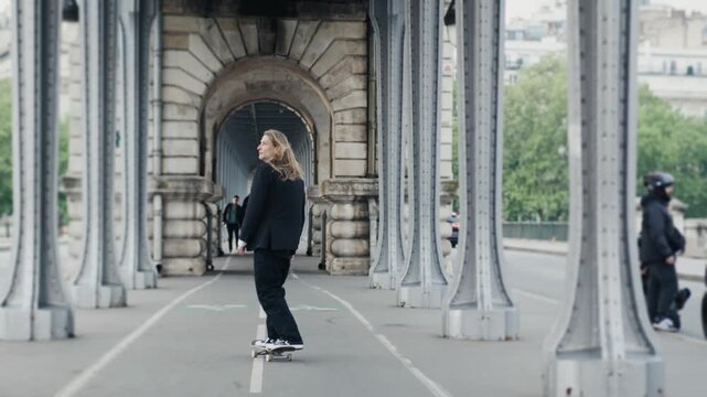 Young businessman skateboarding on pont de bir-hakeim in paris