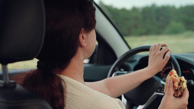 woman girl eating burger car, happy person, Woman eating burger while driving a car, Enjoying fast food on the go, Safe driving with snack, Lunch break in the car, Modern lifestyle image, Quick bite