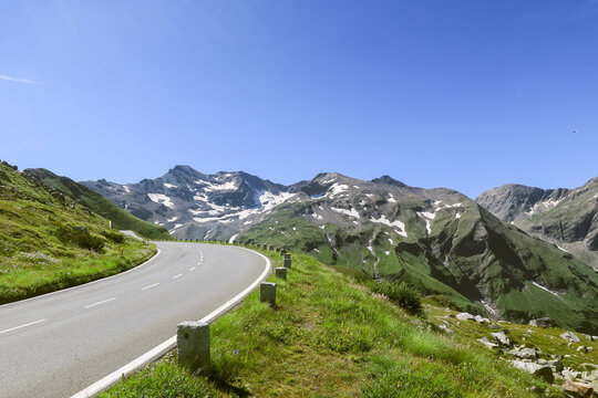 Empty curving mountain road with snow patched peaks