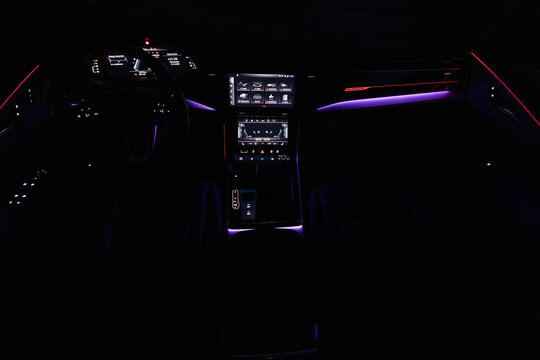 Hybrid electric car Interior view in the cabin. Black leather cockpit with ambient light. Car interior from driver seat view. Cockpit with exclusive decoration. Touch panel climate control.