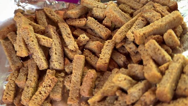 Savory homemade rye bread croutons sliced into thin sticks and placed on foil with crispy texture and appetizing snack atmosphere.