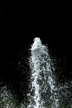 Water fountain shooting into the air with a black background, with copy space