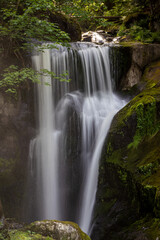 Fototapeta premium Triberger Wasserfälle im Schwarzwald mit sonnenbeschienenem, herabstürzendem Wasser und moosbewachsenen Felsen