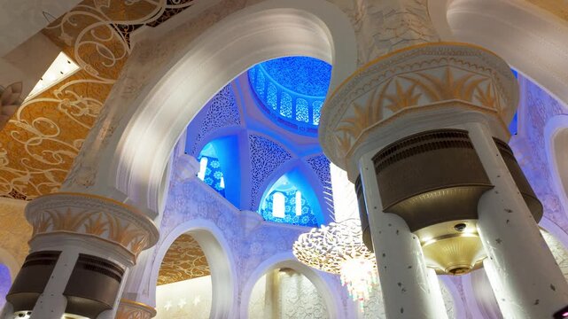 Stunning Islamic geometric patterns, gold leaf carvings, and majestic columns under glowing blue ambient lighting inside the Grand Mosque.