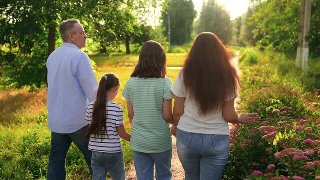 Happy family, man woman children park, girl child sister parents mom dad park, father daughter holding hand children laughing, warm sunset light on a relaxed family walk, family walk during the golden