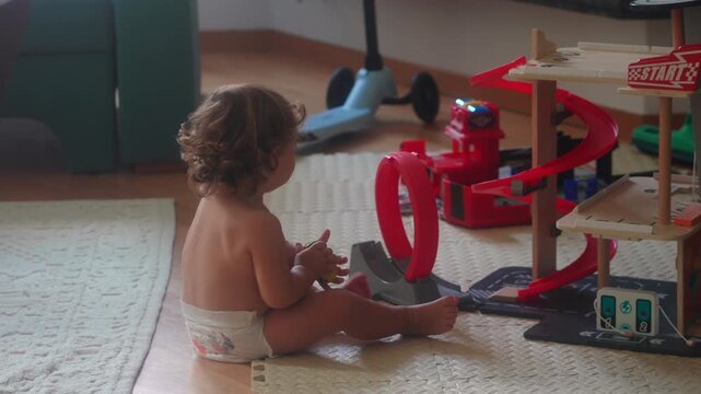Toddler playing with toy car track on floor during morning playtime at home in living room focusing on fine motor skills and early childhood cognitive development