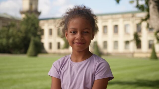 African American little girl child thinking outdoors smiling looking at camera ethnic kid dreaming cute student primary elementary school studying pupil schoolgirl in city positive daughter portrait