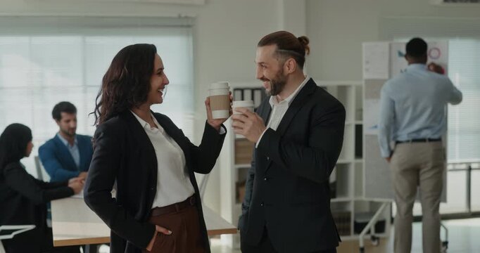 Portrait of Latin and Middle Eastern business colleagues share coffee break after teamwork session. Workers raise cups together and smile during conversation