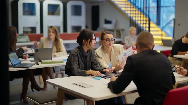Business professionals engage in a collaborative meeting, discussing ideas and analyzing documents in a modern office environment. Colleagues work together to brainstorm strategies for a new project.