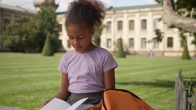Little girl African American child read book prepare lesson elementary school outdoor kid daughter take copybook backpack knowledge student female schoolgirl pupil study learn homework primary class