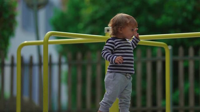 Toddler stepping carefully beneath playground roundabout rail at park capturing balance, coordination and authentic outdoor childhood exploration