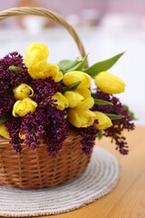 Obraz premium Beautiful flowers in wicker basket on wooden table indoors, closeup