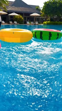 Pink flamingo pool floaties swimming in clear blue water on sunny day