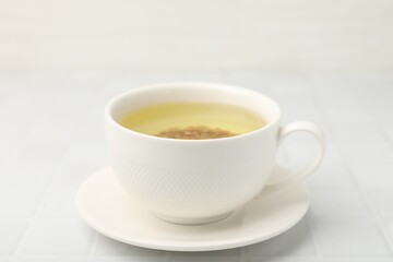 Obraz premium Buckwheat tea in cup on white tiled table, closeup