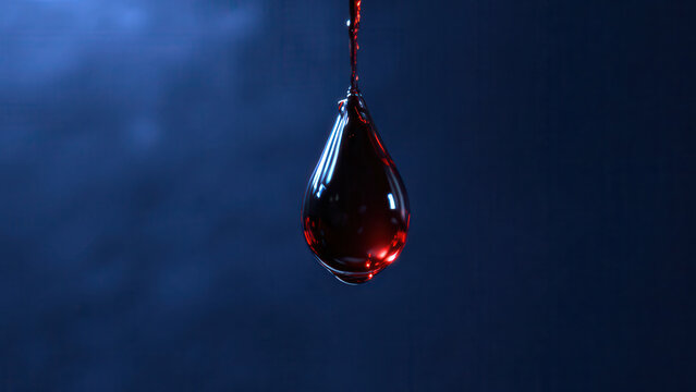 A large, luminous red liquid drop hangs, fed by a thin stream, against a deep blue background, showcasing fluid dynamics.