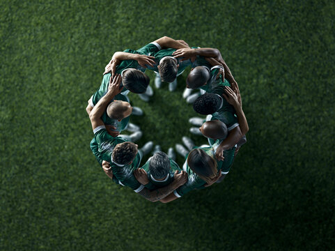 Team gathers in a circle for strategy discussion before a match on a green sports field