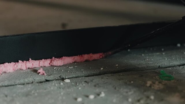 Applying expanding foam insulation beneath metal door frame close up
