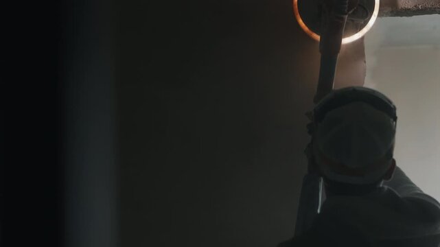 Worker sanding interior ceiling with electric drywall sander close up