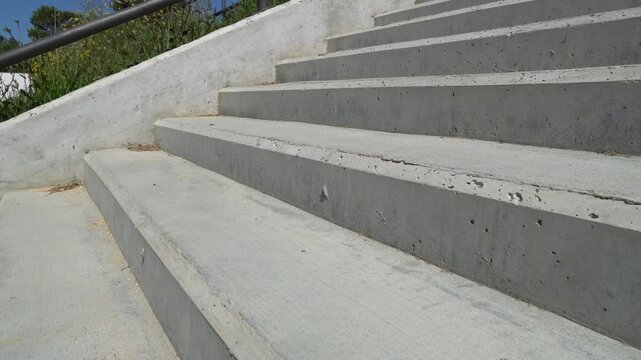 Low angle view of an amputee with a modern prosthetic leg walking down a flight of concrete stairs. The concept shows resilience and recovery