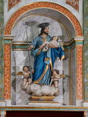 Obraz premium Religious statue of Saint Joseph with child Jesus and angels inside ornate church altar architecture