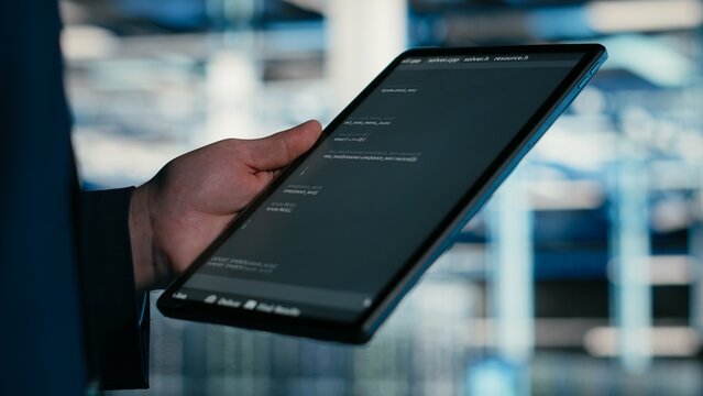 Close up of data center engineer using tablet to write code, compiling software patches to fix bugs, Server farm IT professional using device application to run programming script, camera B.