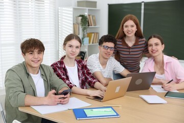 Fototapeta premium Group of students studying with laptops and notebooks at wooden desk in classroom