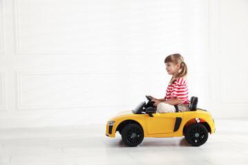 Fototapeta premium Little child driving toy car at home, space for text