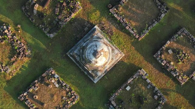 Aerial view of the ancient Plaosan Kidul Temple stupa and surrounding stone ruins on green grass in Kecamatan Prambanan, Jawa Tengah, Indonesia.