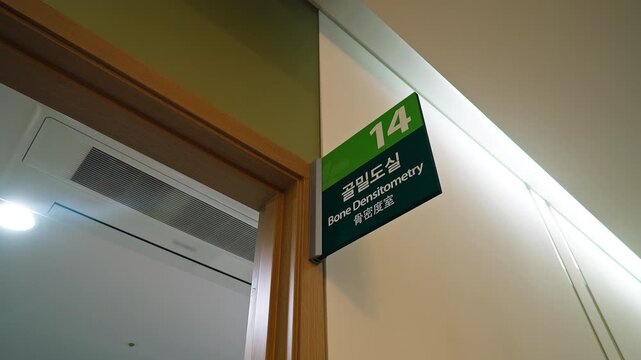 The board in the wall with text "Bone Densitometry" in the English, Korean and Chinese languages. Medical and care.