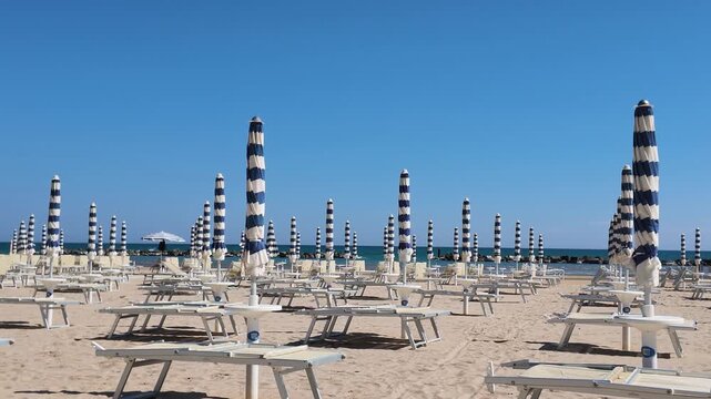 Sunny sandy beach ready for summer season, with umbrellas closed and no people. Italy, Senigallia