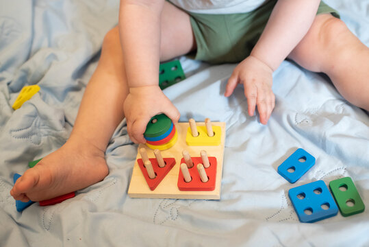 Tiny child sorting colorful geometric blocks on wooden peg board