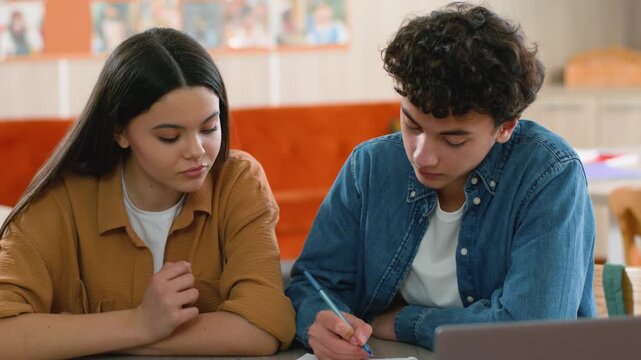 Two Caucasian students puzzled girl boy in school prepare exams difficult study friends worried classmates concentrated solving learn task writing note problem upset homework woman female guy male man