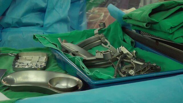 Surgical clamps and medical equipment on green surgical tray inside operating room.