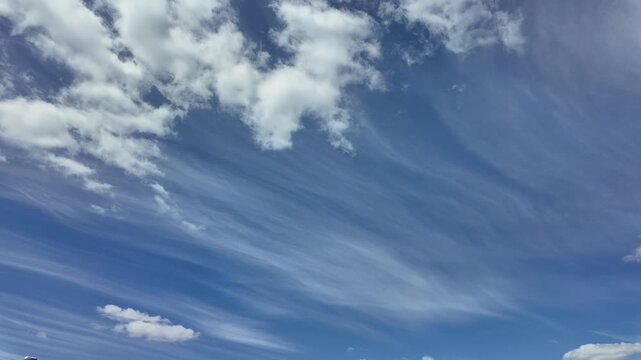 White clouds moving fast from right to left time-lapse. Daylight cloudy heaven background. Long timelapse light clouds transforming in blue sky with motion blur. Perfect for text, titles, logo