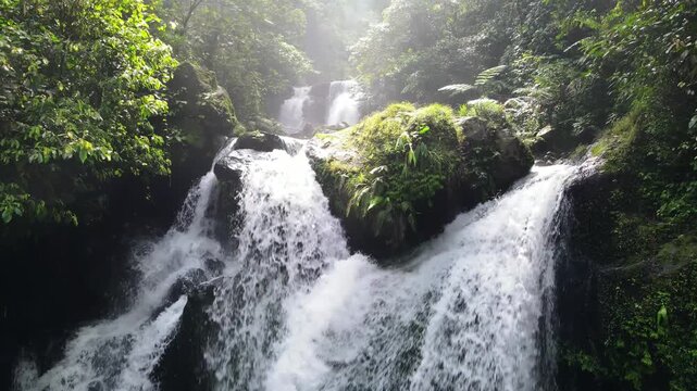 Aerial view of Ambyar waterfall cascading over dark rocks surrounded by lush tropical greenery in Purwokerto, Central Java, Indonesia.