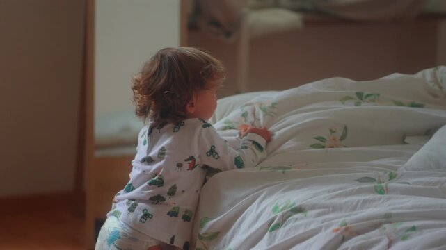 Toddler touching moving duvet during playful sibling hide and seek game in cozy bedroom capturing curiosity, imagination and authentic childhood family fun