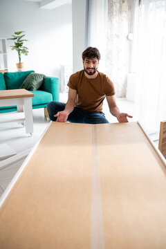 Man assembling flat-pack furniture in living room