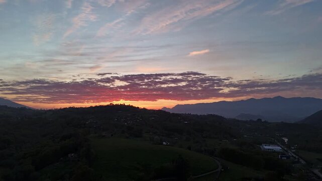 Aerial hyperlapse of spectacular sunset over Cangas de On&iacute;s hills, Asturias, Spain. Vivid red, orange and purple sky with cirrus clouds above silhouetted hills and Picos de Europa. DJI Mini 4 Pro, 4K.